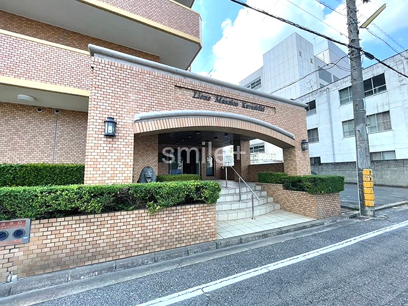ライオンズマンション倉敷 重厚感のあるレンガ調の外壁が特徴のエントランス。植栽の緑と門灯が、住まいの顔を穏やかに彩ります。